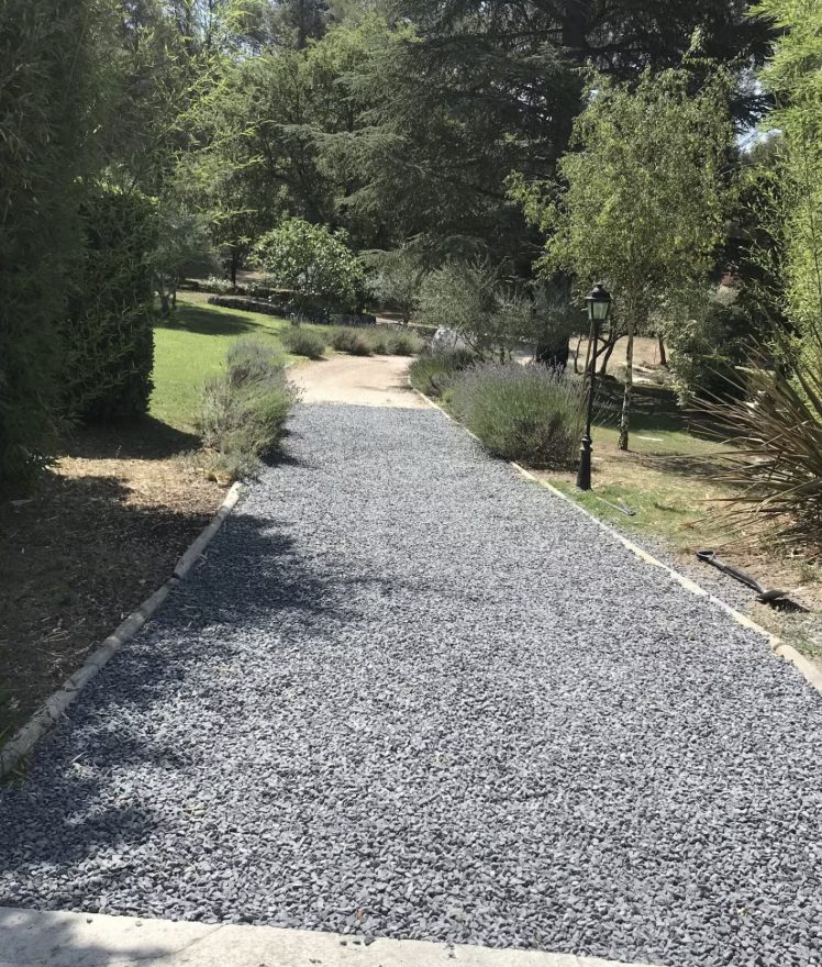 Allée de jardin en gravier avec plantations et arbres